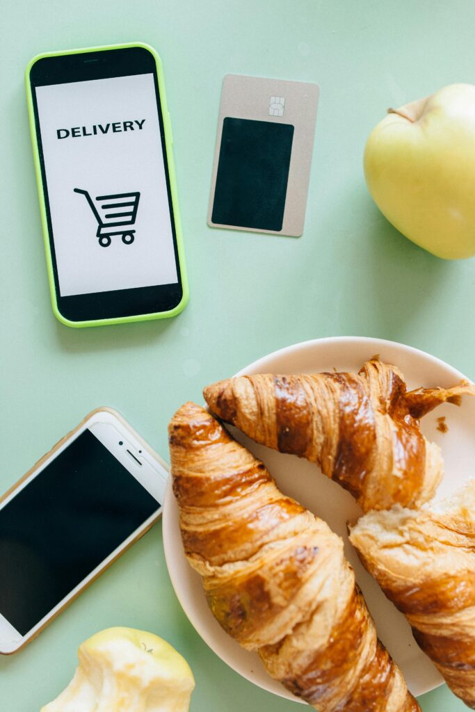 Vale-alimentação x Vale-refeição: Diferenças, Obrigações e Direitos 14 Flat lay of croissants, smartphones, and an apple showcasing a delivery concept.