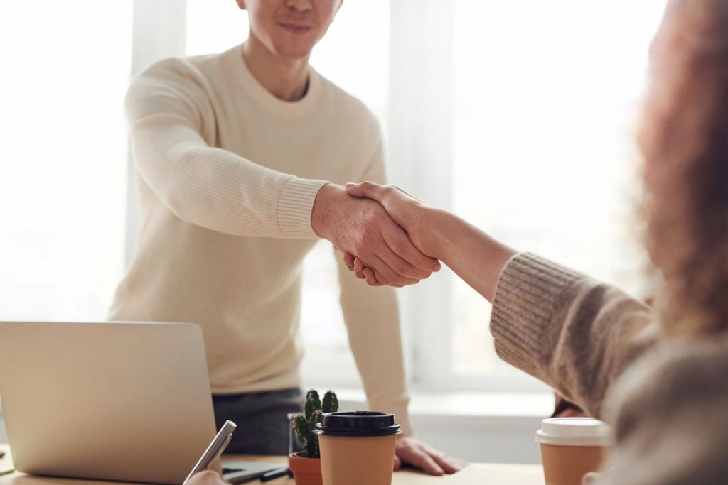 RH na Era da IA: como acelerar a seleção e contratar melhores profissionais com Inteligência Artificial 4 Recrutador cumprimentando candidato aprovado em entrevista de emprego — RH na era da IA